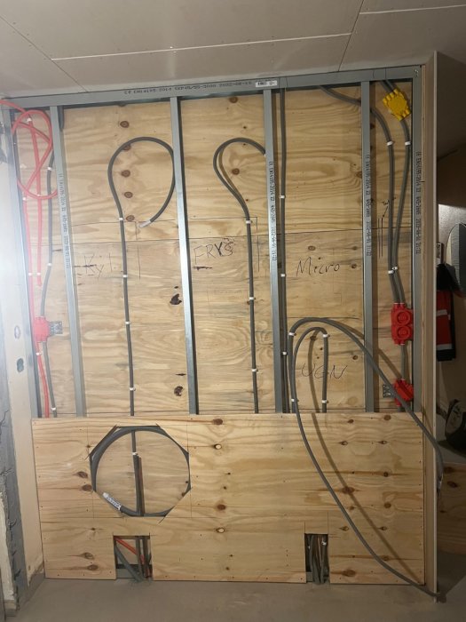 Byggarbetsplats med osynliga väggar, elinstallation, träskivor, rörmärkningar och konstruktionsmaterial.