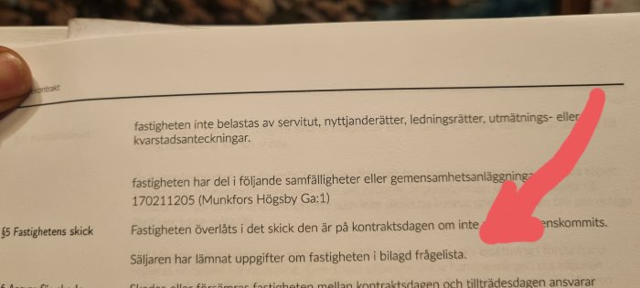 Svenskt juridiskt dokument, text om fastighetsrättigheter, med rosa markering och hand synlig.