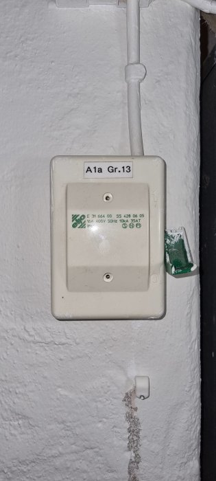 En öppen elektrisk kopplingslåda med kablarna exponerade på en vitmålad vägg.