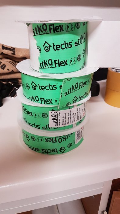 Staplar av grön tejp med text "tectis siltkQ Flex", ligger på vit yta.