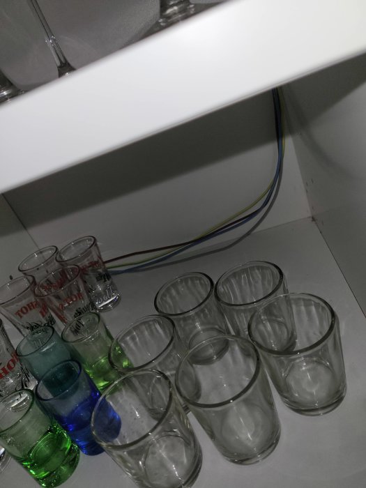 Skåp med glas, några färgade, kabelrör. Otydlig bildvinkel, överskådar syn.