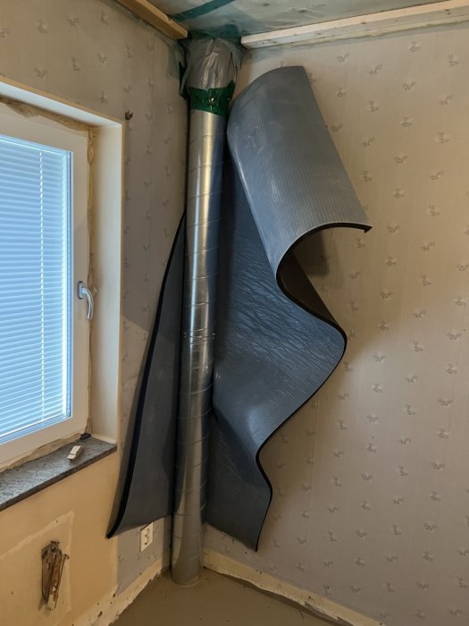 Ett rum under renovering med oavslutat tak och synlig ventilationsslang som hänger ner.