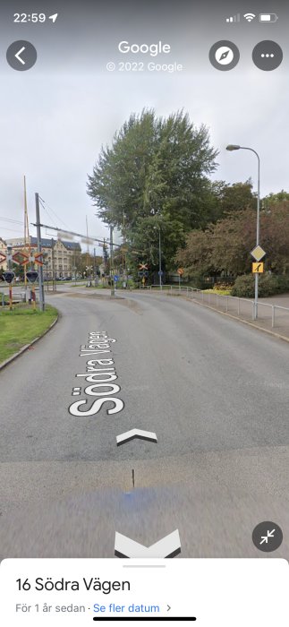 Gatuvy från Google Maps som visar en vägkorsning med skyltar, träd och en järnvägsövergång.