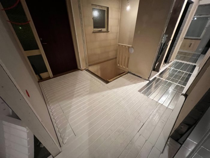 Interiör trappuppgång på kvällen, öppen dörr, trappor, mixad belysning, reflekterande ytor, otydlig avspegling.
