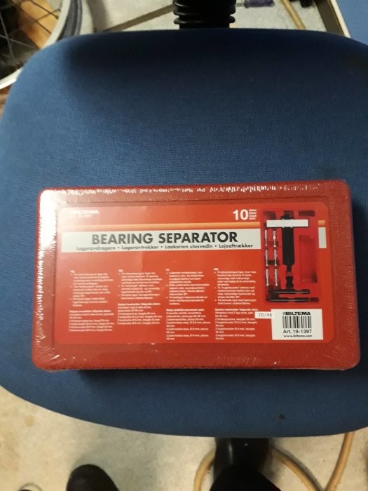 Röd förpackning med verktyg "BEARING SEPARATOR" på en blå stol, med text på flera språk, Biltema-varumärke.