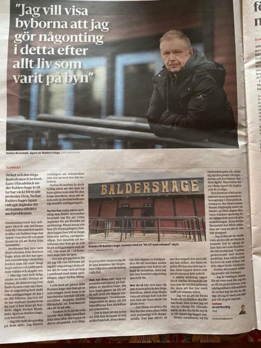 Man lutar sig mot räcket framför byggnaden med skylten "BALDERSHAGE". Artikel om lokalt ägarbyte och byutveckling på svenska.