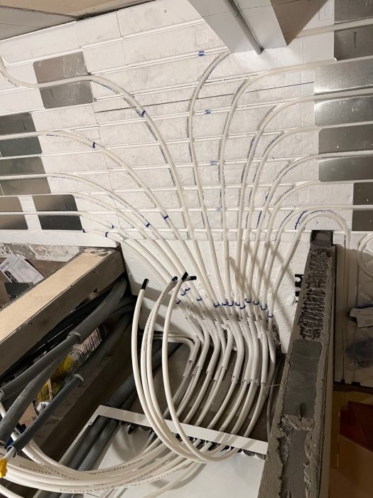 Installation av vita plaströr för elkabeldragning i en vägg under konstruktion.