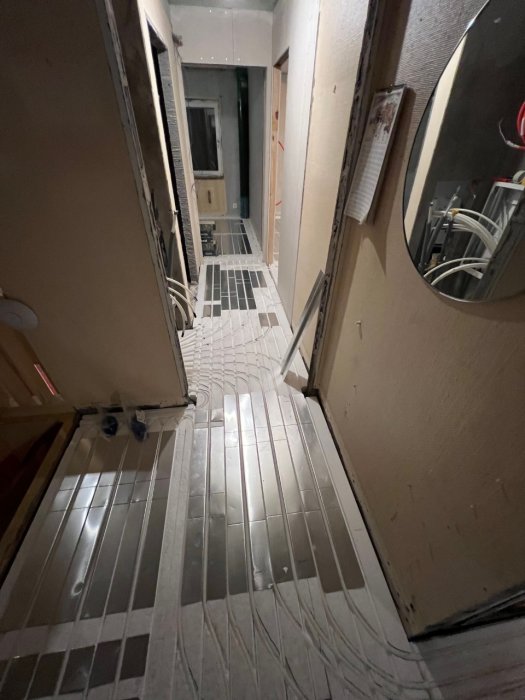 Ett smalt utrymme inne i en byggnad under renovering med synliga elledningar och avskalade väggar.