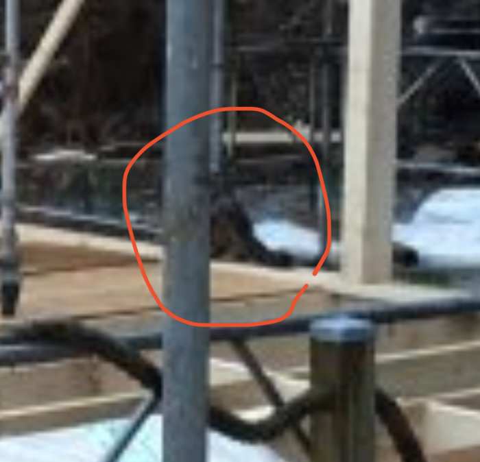 Suddig bild av en utomhusmiljö med metallstänger, cirkelmarkerat område drar fokus, bakgrundens detaljer är otydliga.