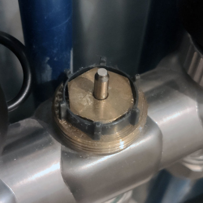 Metallventil med fäste på rör, industriell komponent, närbild, mekaniska detaljer, ingen synlig människa.