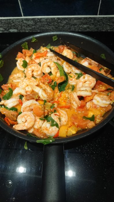 Stekpanna med räkor, grönsaker, tomatsås. Sund, färgglad matlagning. Hemmakök.