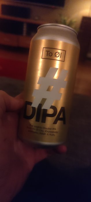 En hand håller en burk öl med texten "DIPA" i en inomhusmiljö.