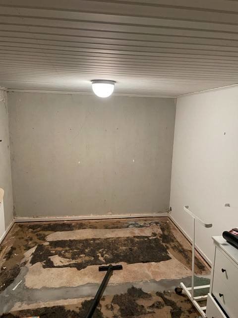 Ett tomt rum under renovering med borttaget golv och vitmålade väggar.