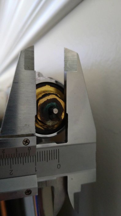 Skjutmått mäter en objekts diameter, troligen inom ingenjörsväsende eller mekanisk kontext.