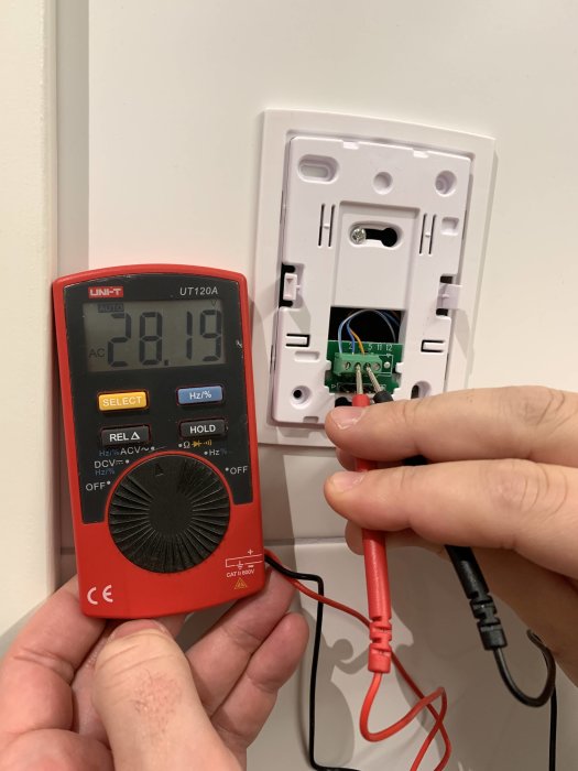 Mätning av spänning med multimeter vid en öppen eluttag.