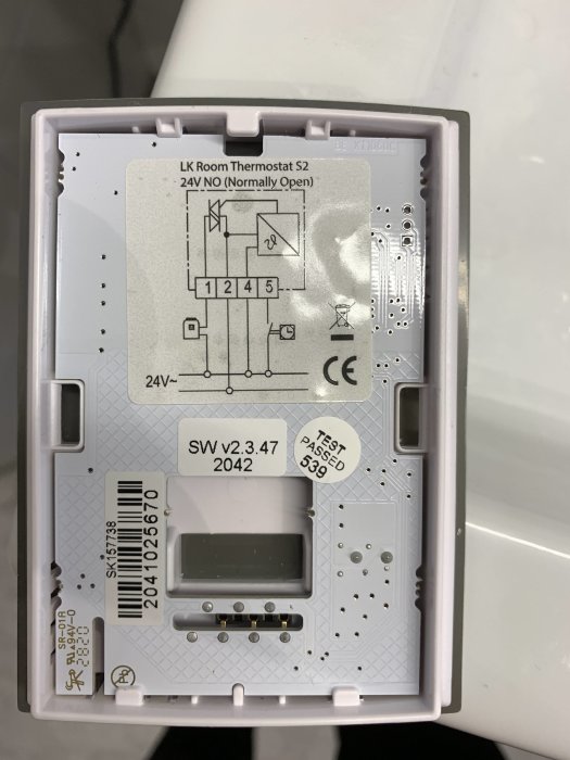 Öppet termostatlock med installationsanvisningar, kretsschema, versionsetikett och ett godkänt testmärke.