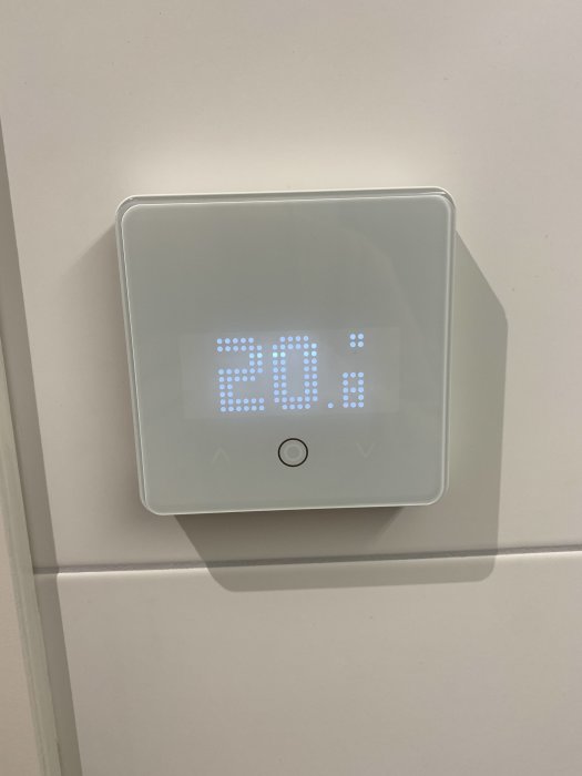 Väggmonterad digital termostat som visar temperaturen 20.5 grader Celsius i ett modernt gränssnitt.