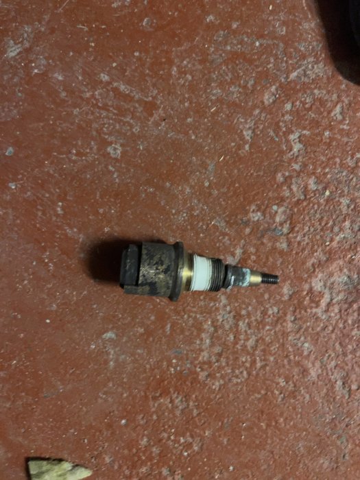Använd tändstift på rödbrun bakgrund, möjligtvis utbytt eller kontrollerat, verkstadsmiljö.