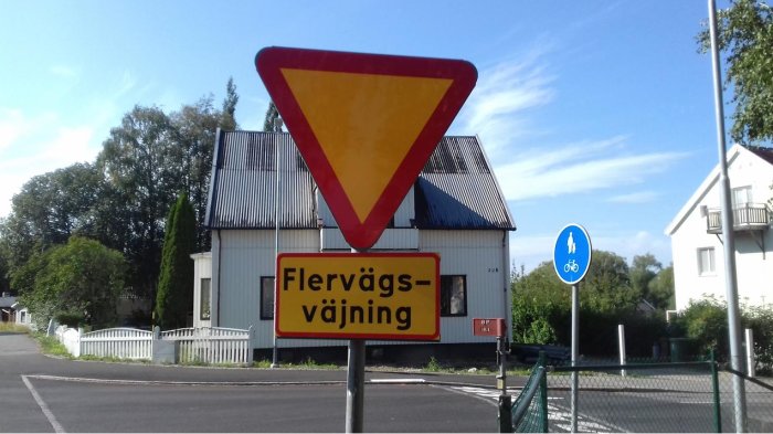 Vägskyltar, hus, träd, klar himmel, "Flervägsväjning" varning för korsning, gång- och cykelvägsskylt.