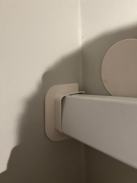 Vit hörnhylla på en vägg, detaljbild, skuggspel, minimalistisk design, inomhus.