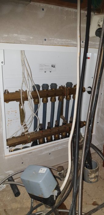 Uppvärmningssystem med kopparrör, golvvärme fördelare, kablar, oorganiserad installation, underhållsbehov.
