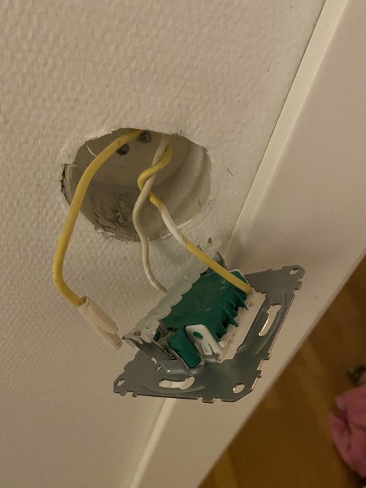 Öppen elinstallation, uttag halvt monterat i vägg, synliga kablar och isolering, osäkerhet.