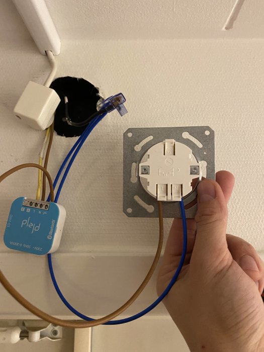 Elinstallation, vägguttag utan kåpa, Plejd enhet, elledningar, hand som håller, oavslutat arbete, väggöppning.