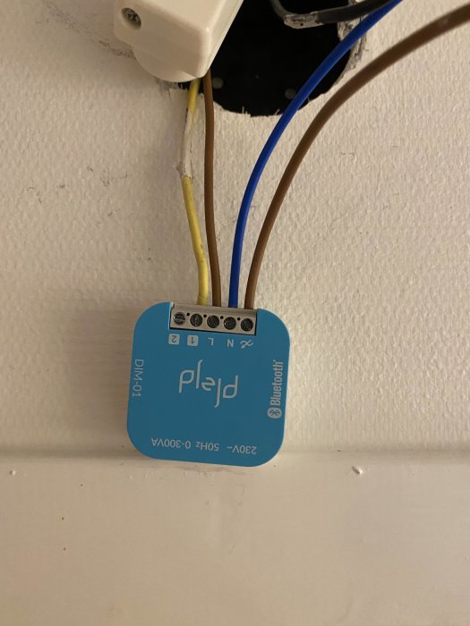 Elektrisk enhet, troligen en dimmer, med ledningar, på en vägg utan täckplatta.