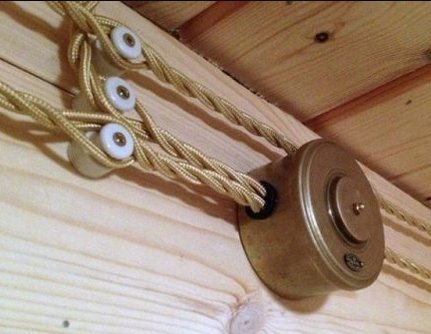 Rullskena i tak med rep genom öglor som liknar ögon på träyta. Lichtschalter-Schieber_modern.