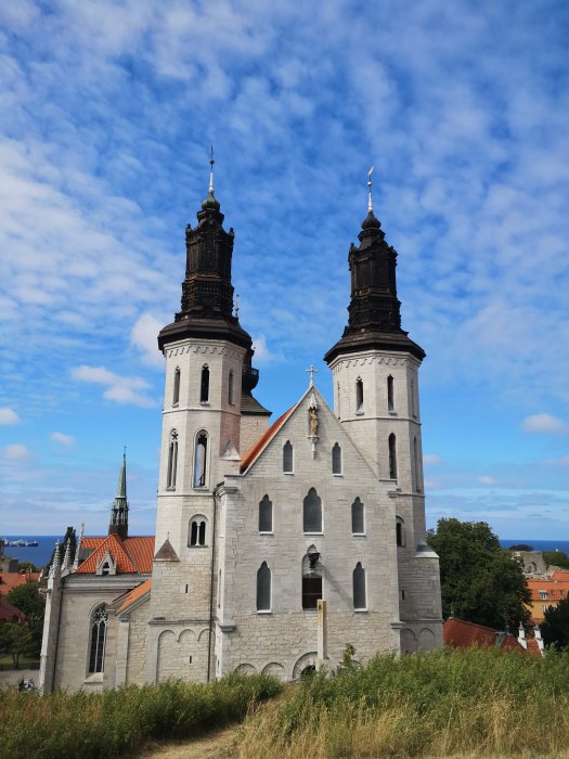 Tvillingtorn, kyrka, blå himmel, vita moln, grönt gräs, arkitektur, dagtid.