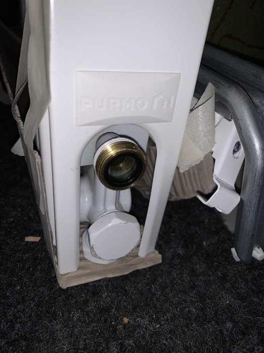 Radiatorkoppel med avtagen termostatknopp, PURMO-märke, på en grå matta.