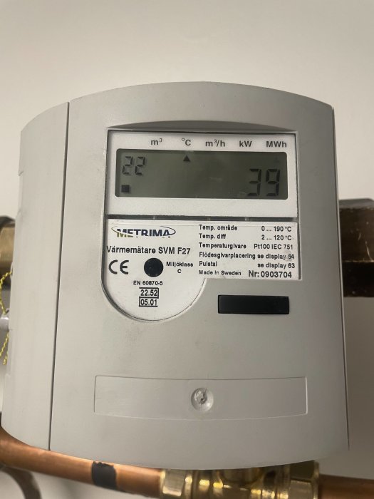 Värmemätare med LCD-display visar kubikmeter, temperatur, flödeshastighet och energiförbrukning. Monterad på rör, "Made in Sweden."