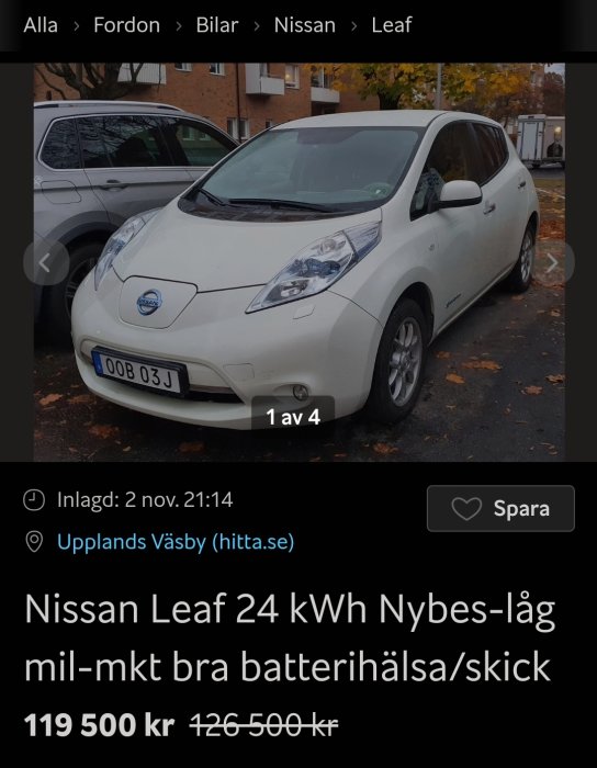 Vit Nissan Leaf elbil parkerad, försäljningsannons, prisnedsänkning, höstträd i bakgrunden.
