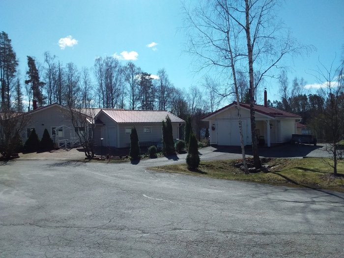 Enframiljshus och garage i ett soligt, lugnt bostadsområde med blå himmel och trädbeklädda bakgrunder.