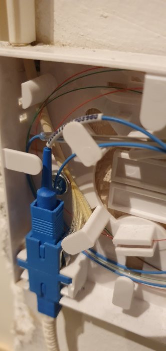 Ett öppet eluttag med synliga ansluta kablar och plastklämmor, delvis genomförd installation eller reparation.