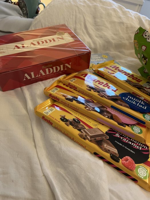 Chokladkakor och askar på säng, Marabou märken, olika smaker, Aladdin ask, mysigt snacks.