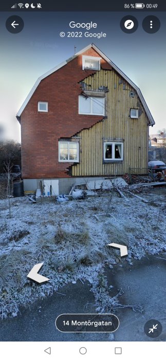 Tvåvåningshus med röda tegel och gula träpaneler, frostigt gräs, vintertid, nedskräpning, renovationsbehov, öde känsla.