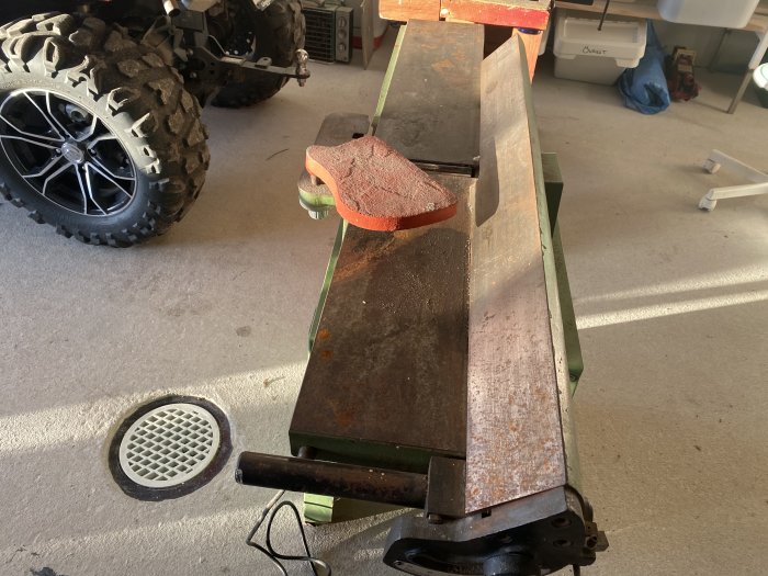 Metallskärare med rost och trä i verkstad, skymt av ATV-hjul.