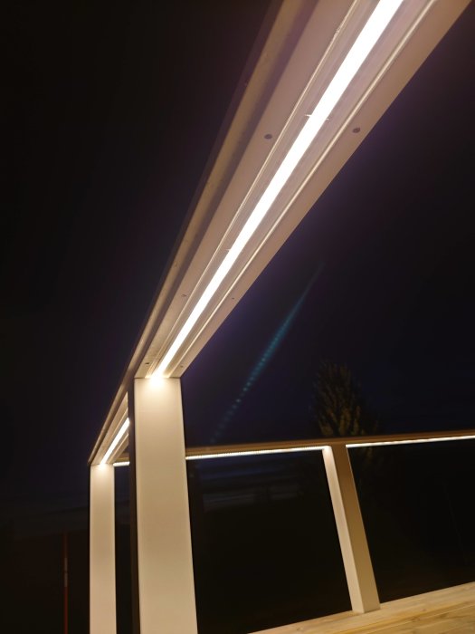 Lysrör under takkant nattetid, mörk himmel, arkitektoniska detaljer, modern design, diffust ljus, bokeh-effekt.