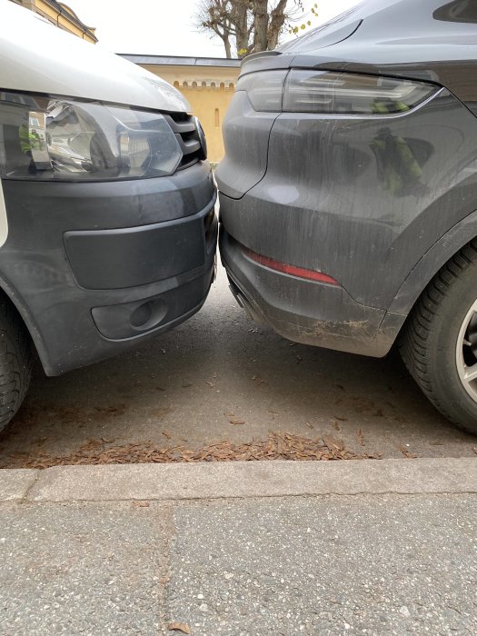 Två bilar parkerade mycket nära varandra, den ena svart och den andra grå.