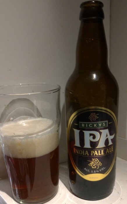 En ölflaska märkt "IPA" bredvid ett glas med skummande öl.