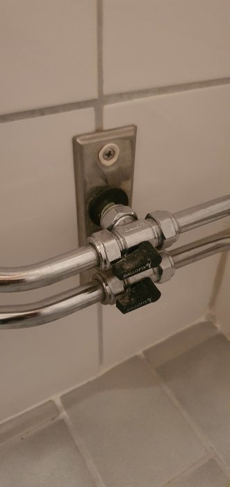 Kromade rör med ventil, Ballofix-märkning, monterade på kakelvägg, badrum eller kök.
