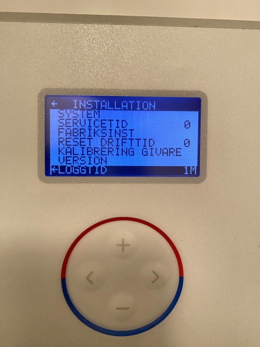 LCD-display med installationsmeny på svenska, fyrvägs navigeringsknapp nedan, modern teknologisk enhet.