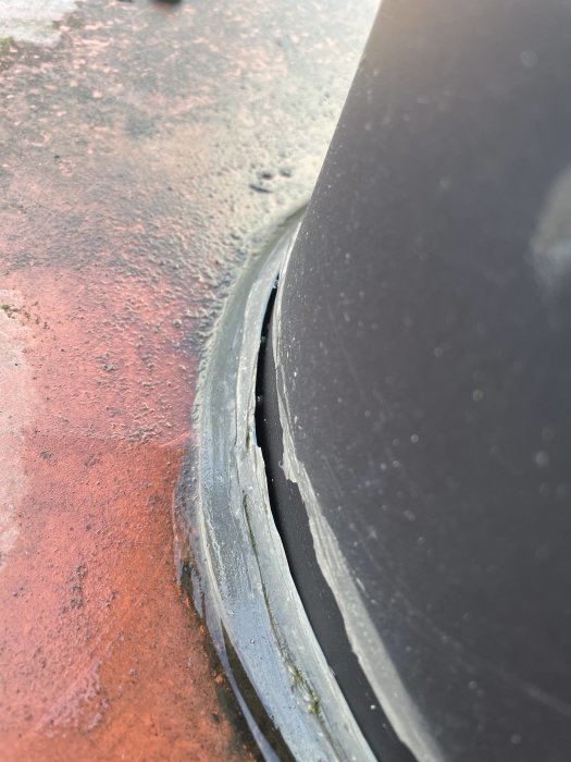 Däck skadat, ur fälg, närbild, slitna markeringar, vägkant, möjligen punktering, underhåll behövs.