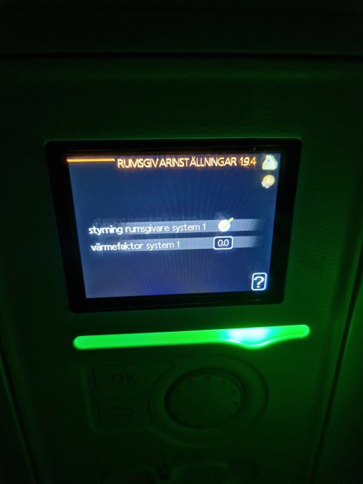 Digital kontrollpanel med meny för rumsvärmeinställningar, grönt ljus, knapp märkt 'OK'.