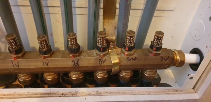 Värmeinstallation, flervägsfördelare med termostatventiler och påskrivna siffror, rörsystem, teknisk utrustning.
