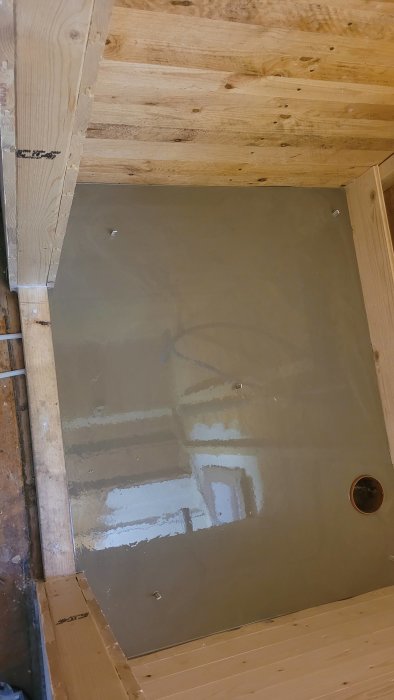 Bild av en hörnig, ofärdig duschplats med betonggolv och synliga träbjälkar.