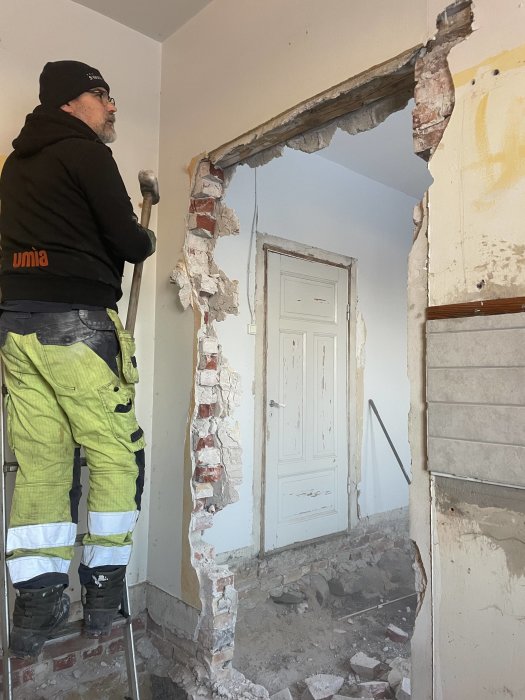 Arbetare river vägg för renovering, byggritning, rör sig, säkerhetskläder, inomhusmiljö, sten, tegel, damm.