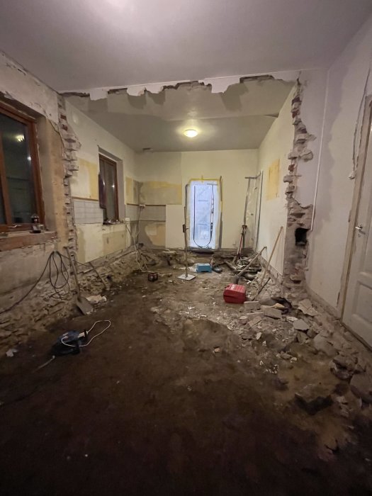 Rivningsarbete inuti hus, utspridda byggnadsmaterial, nedmonterade väggar, rörledningar synliga, stökig miljö.
