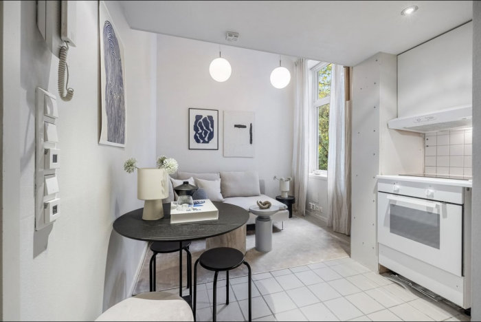 Modernt litet kök och vardagsrum. Vitt, minimalistiskt, konst på väggarna, runda taklampor, matplats, inbyggd vitvaror.